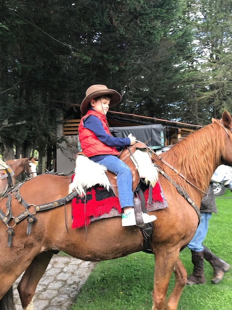 Foto hombre a caballo de pie junto a un árbol