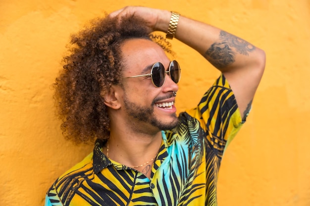 Hombre con cabello afro en verano verano en una camisa de palmera sobre un fondo amarillo