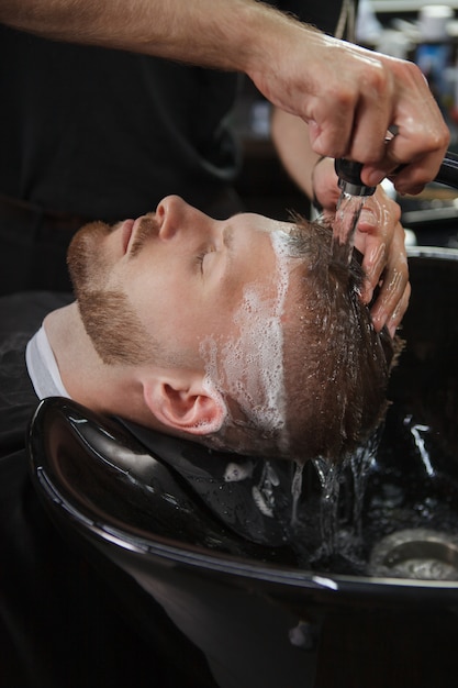 Hombre con cabello lavado por peluquero profesional