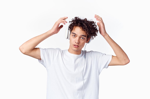 Hombre con cabello rizado escuchando música con auriculares camiseta de nueva tecnología de moda adolescente