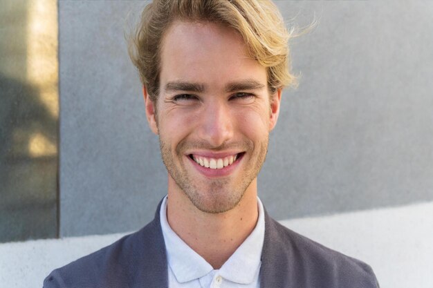 un hombre con cabello rubio sonriendo y una camisa blanca