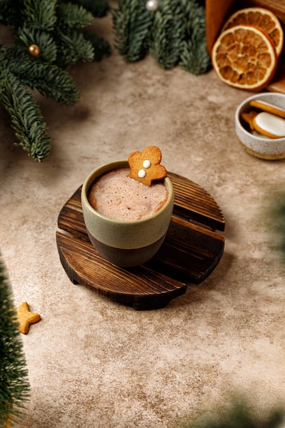 Hombre de cacao con jengibre en un vaso de cerámica. Árbol de Navidad en el fondo. Colores beige