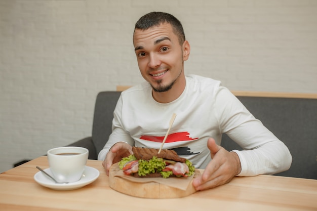 Hombre en cafe comerá sandwich