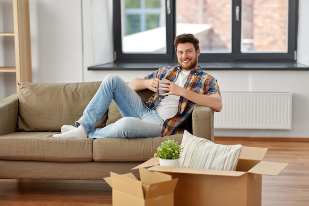 Foto hombre con cajas y bebiendo café en la nueva casa