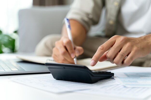 Foto el hombre está calculando el impuesto anual con una calculadora y llenando el formulario de la declaración del impuesto sobre la renta individual