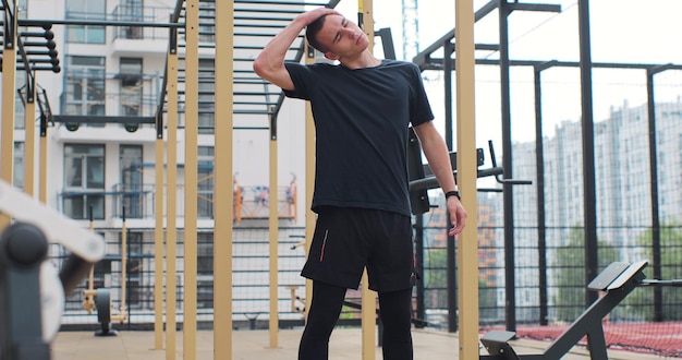 Hombre calentando su cuello y cabeza antes de entrenar en un campo deportivo Deportista haciendo ejercicio Concepto de estilo de vida saludable