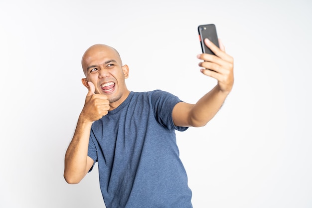 Hombre calvo asiático feliz mostrando los pulgares hacia arriba cuando selfie