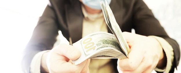 Un hombre calvo con una máscara sostiene una pila de billetes de cien dólares Pago de seguro y crédito