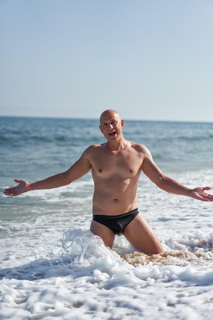 Foto hombre calvo en la playa junto al mar de vacaciones
