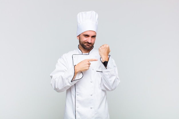 Hombre calvo que parece impaciente y enojado, señalando el reloj, pidiendo puntualidad, quiere llegar a tiempo