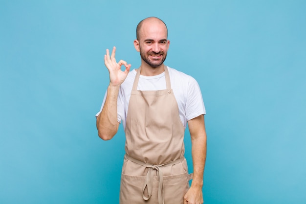 Hombre calvo que se siente feliz, relajado y satisfecho, mostrando aprobación con gesto bien, sonriendo