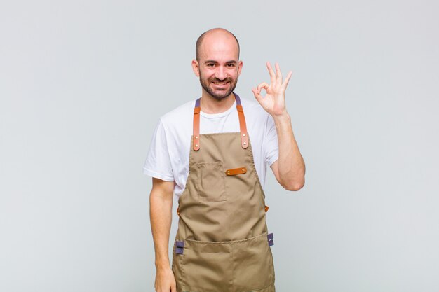 Hombre calvo que se siente feliz, relajado y satisfecho, mostrando aprobación con gesto bien, sonriendo