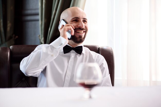 Un hombre calvo en un restaurante hablando por teléfono.