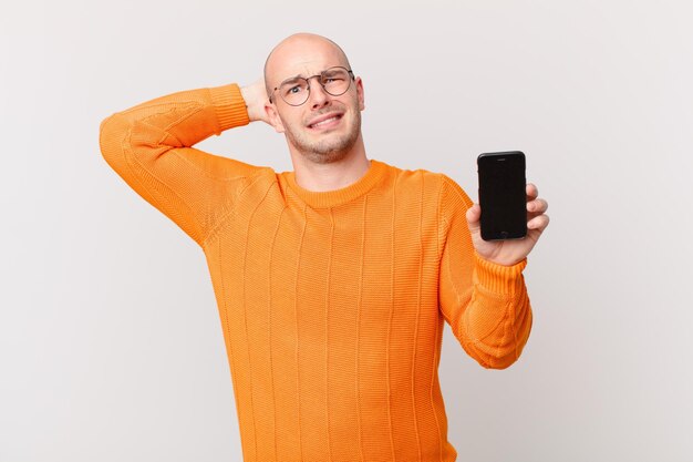 hombre calvo sosteniendo una pantalla de móvil