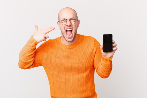 Hombre Calvo con un teléfono inteligente contra la pared aislada