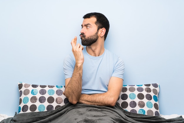 Hombre en la cama con los dedos cruzados y deseando lo mejor