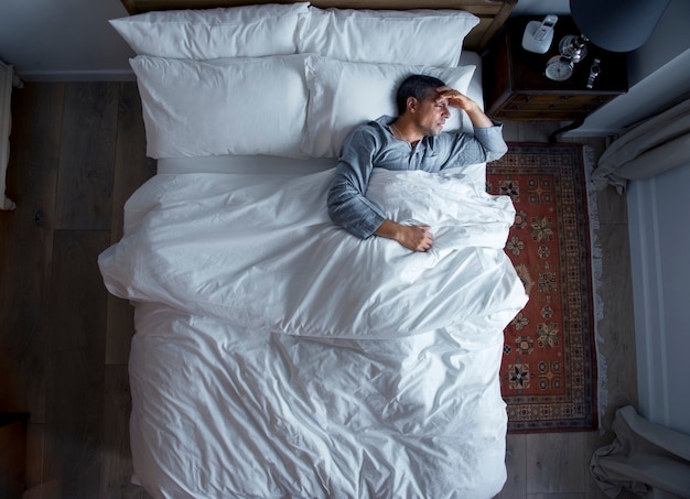 Hombre en la cama con dolor de cabeza