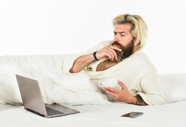 Hombre en la cama trabajando en la computadora por la noche Gerente de proyecto Terminando el trabajo en la cama Hombre trabajando en la computadora portátil y el teléfono en la cama Hombre pasando tiempo en la habitación usando el concepto de estilo de vida relajante de la PC