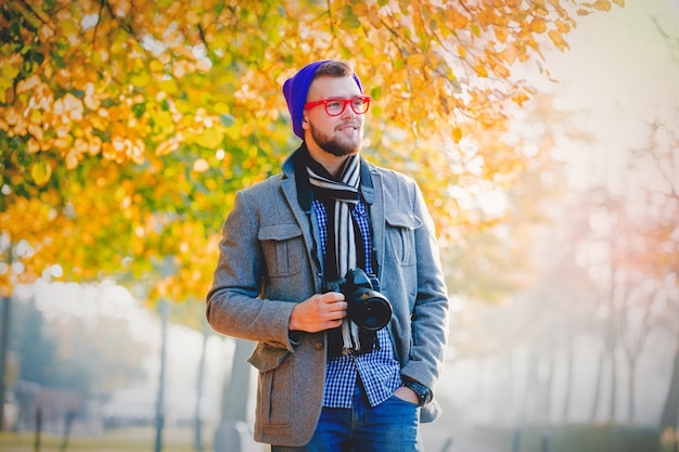 Hombre con cámara en el callejón de la temporada de otoño