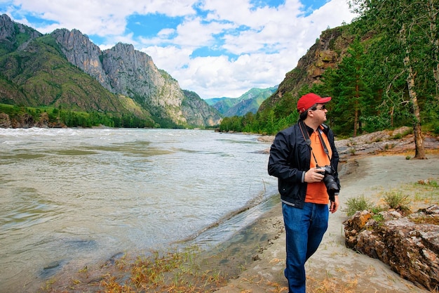 Hombre con cámara en el río Katun y las montañas de Altai en Siberia en Rusia