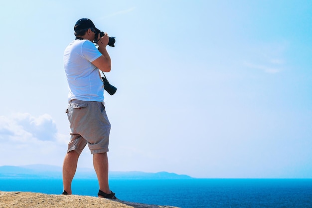 Hombre con cámara tomando fotos del mar Mediterráneo en Capo Testa, Santa Teresa Gallura, Cerdeña, Italia