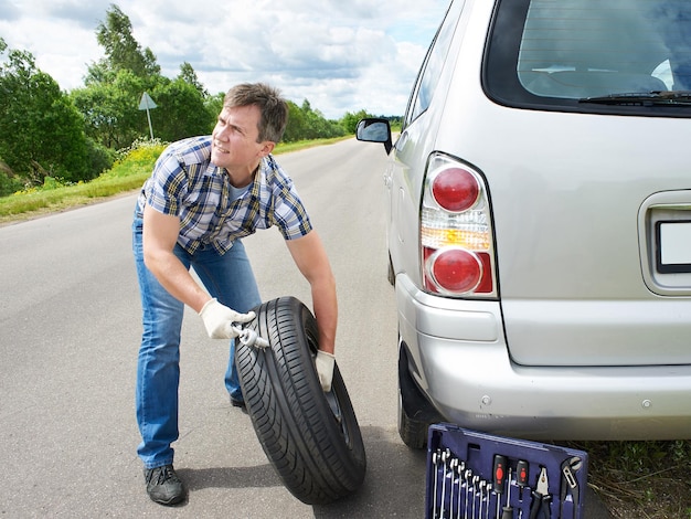 Hombre cambiando rueda de coche