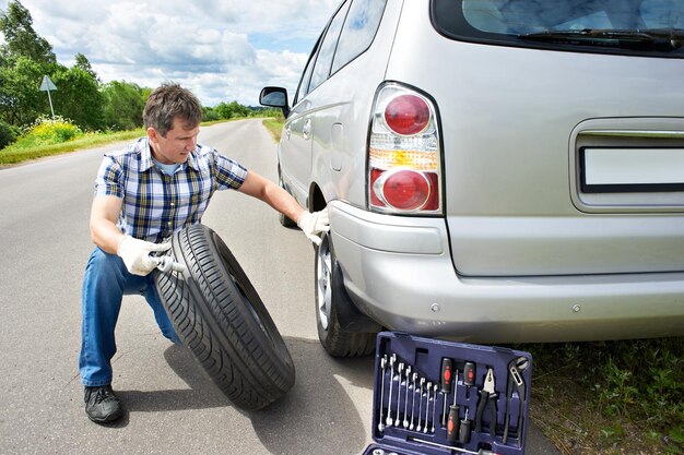 Hombre cambiando rueda de coche