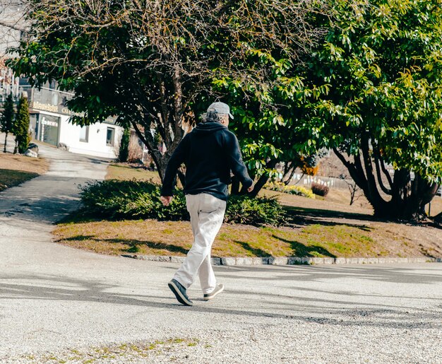 Foto un hombre camina por una calle con un árbol al fondo.