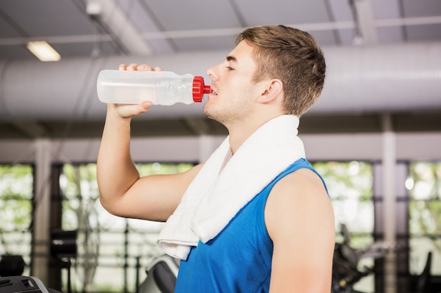 Hombre en caminadora agua potable en el gimnasio