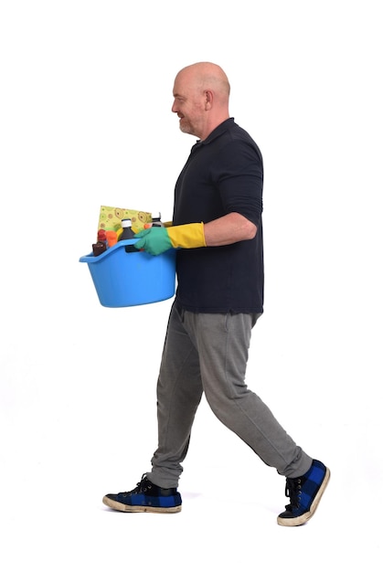 Hombre caminando con un balde y productos de limpieza sobre fondo blanco.
