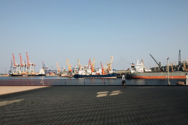 Foto hombre caminando por los barcos amarrados en el muelle comercial