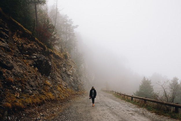 Hombre caminando en la montaña en un día de niebla en la montaña en invierno