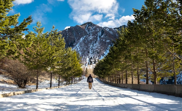 Un hombre caminando hacia una montaña en invierno.