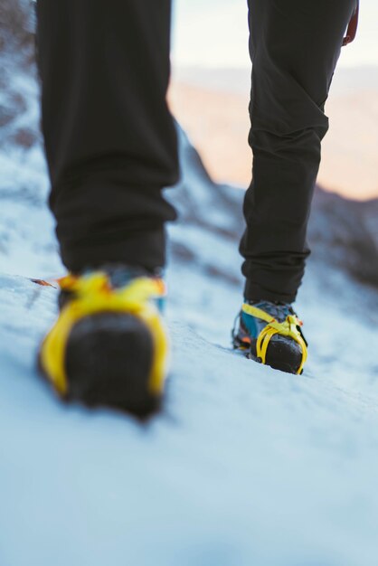 Foto hombre caminando en la nieve con crampones