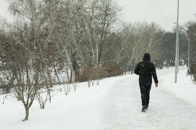 Hombre caminando en el parque en un increíble clima invernal