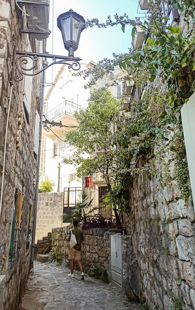 Hombre caminando en una pequeña calle con edificios de piedra en el casco antiguo de Kotor, Montenegro