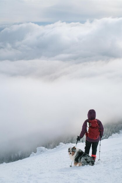 Hombre caminando con perro en un hermoso bosque de invierno en la montaña