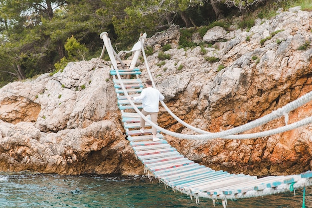 Hombre caminando por el puente colgante espacio de copia de horario de verano