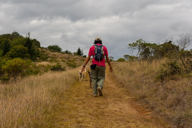 hombre caminando por un sendero de montaña junto a sus perros con una mochila en la espalda