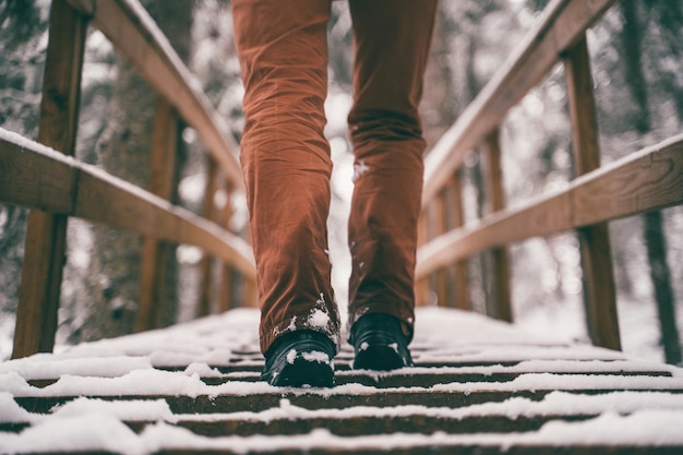 Hombre caminando sobre un puente nevado de madera en invierno