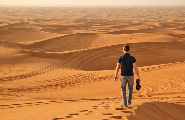 Hombre caminando solo en el desierto soleado junto a Dubai