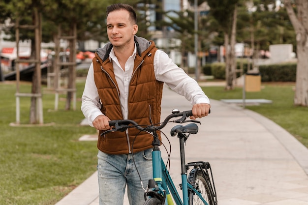 Foto hombre caminando con su bicicleta junto a él