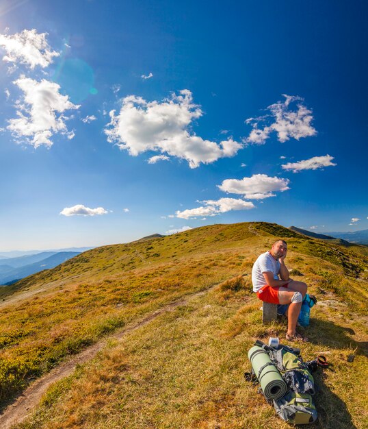 Hombre caminante de pie en la cima del pico rocoso con vistas al paisaje de montaña.