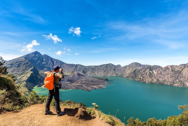 Hombre caminante con el volcán activo Baru Jari y la cumbre de la montaña Rinjani.