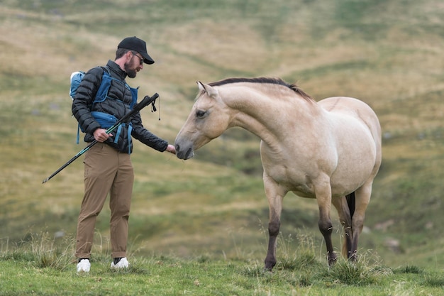 El hombre durante una caminata le da hierba a un caballo