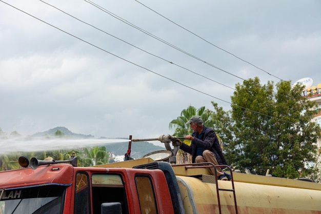 Foto un hombre en un camión con un barril de agua vierte agua sobre los escombros para mantenerlos libres de polvo