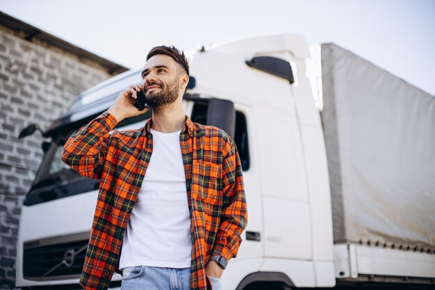 Foto hombre camionero hablando por teléfono junto a su camioneta blanca