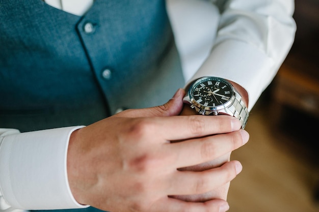 Un hombre con una camisa ajusta el reloj en su brazo Cerca de un hombre de negocios usando un reloj