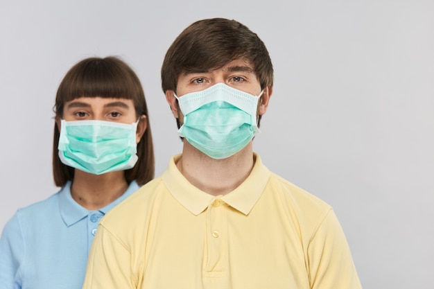 Hombre con camisa amarilla y máscara respiratoria mirando a la cámara y niña con máscara de protección detrás, aislamiento del virus corona, espacio de copia