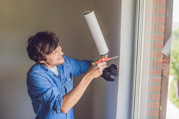 El hombre con una camisa azul hace la instalación de la ventana. Usando una espuma de montaje.